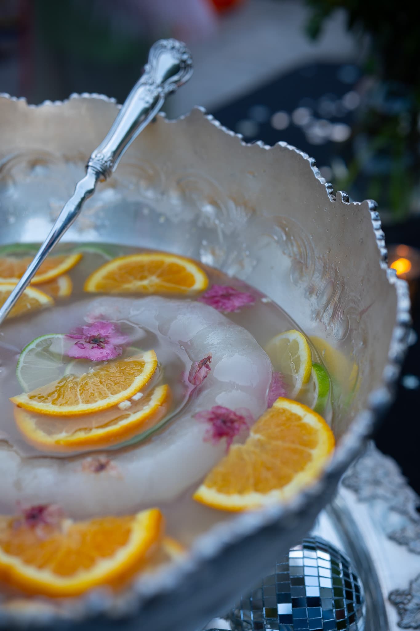 Silver punch bowl with citrus slices and flowers