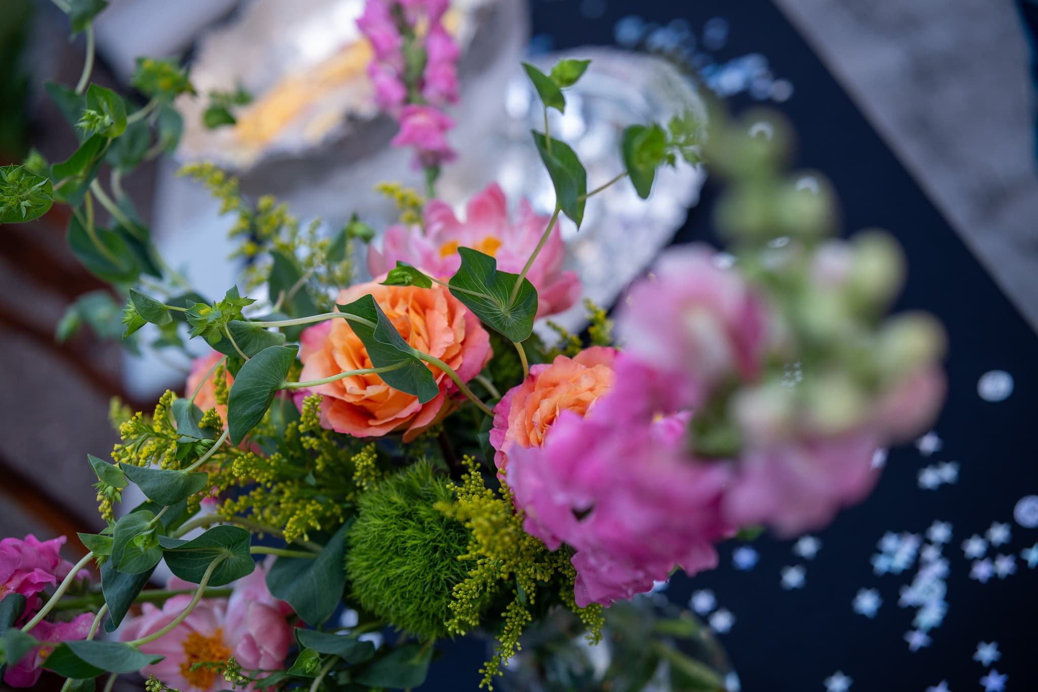 Close-up outdoor floral arrangement with orange roses and pink peonies