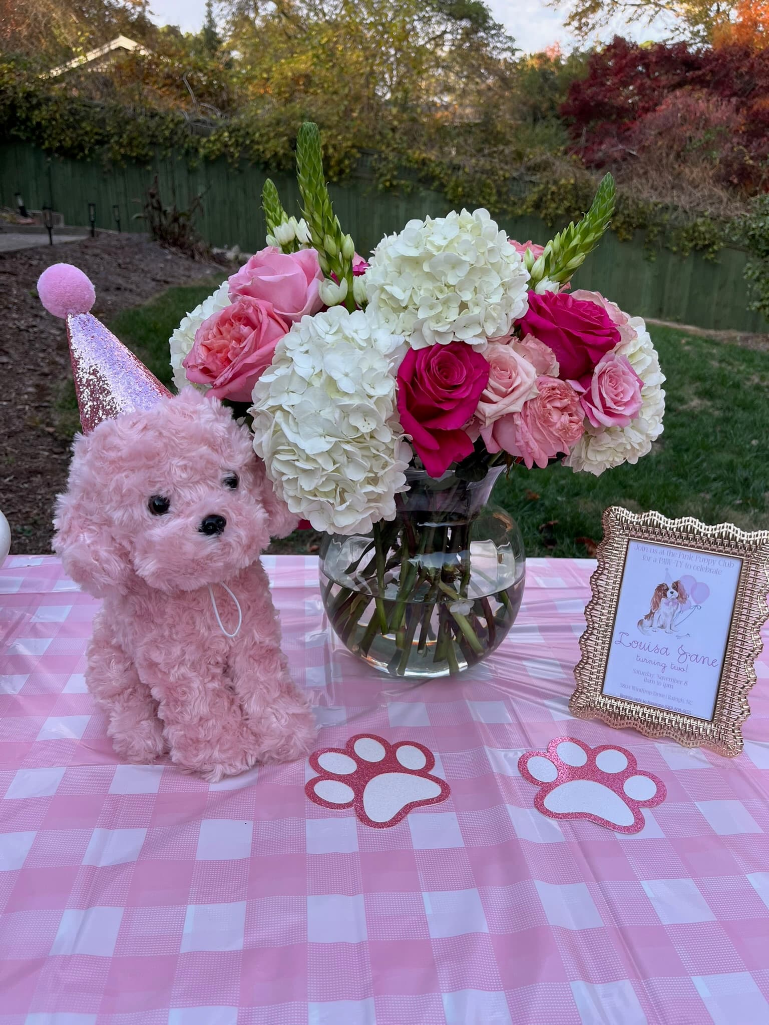 Pink puppy birthday table with flowers and a party hat stuffed animal